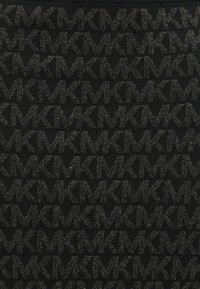 Svart strikket stoff med et gjentakende mønster av bokstavene "KM" i en subtil metallisk tråd, som skaper et teksturert design.