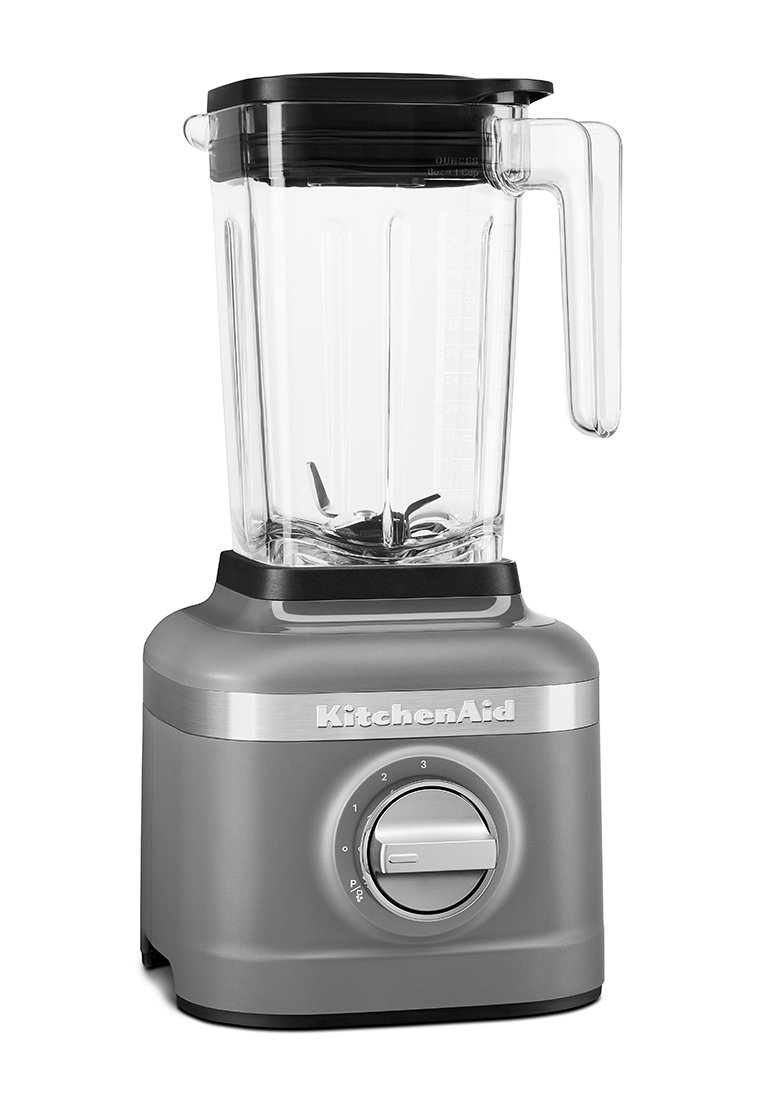 KitchenAid-blender met een doorzichtige glazen kan, zwarte deksel en grijze kunststof basis. Voorzien van een zilveren band en een bedieningsknop met genummerde instellingen.