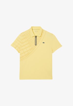 Camisa polo amarilla con cuello con cremallera, que presenta un patrón diagonal texturizado y un logotipo bordado verde en el pecho.