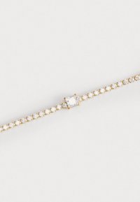 Bracciale in oro con una fila di piccole pietre trasparenti e una pietra quadrata centrale più grande, caratterizzato da un delicato design a catena.