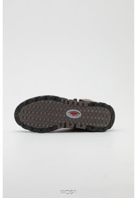 Semelle de botte d'hiver marron avec motif de crampons profonds et logo Tullingsport au centre, présentée sur un fond clair uni.