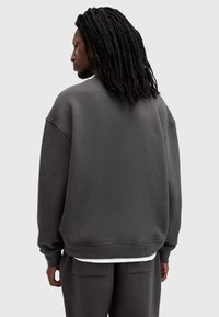 Sudadera de gran tamaño en gris oscuro con cuello redondo, hombros caídos y puños acanalados. Hecha de una suave tela texturizada.