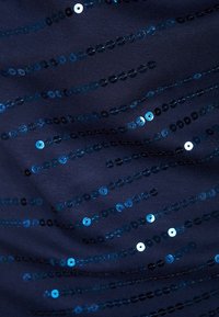 Marinfärgad tyg med horisontella ränder av blå paljetter, som varierar i färg från ljusblå till mörkblå, vilket skapar ett texturerat, glittrande mönster.