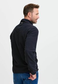 Marineblauer Fleece-Pullover mit Stehkragen. Verfügt über ein dezentes Logo auf der Rückseite und eine glatte Textur. Lange Ärmel und lockere Passform.