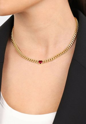 Collana in oro con un design spesso e intrecciato, al centro presenta una piccola pietra preziosa a forma di cuore rosso.