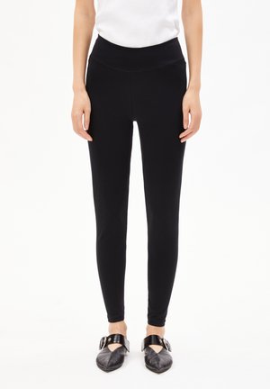 Zwarte leggings met een hoge tailleband, gemaakt van rekbare stof. Glad textuur en aansluitend ontwerp. Draag met zwarte flats.