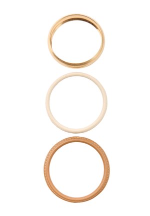 Trzy pierścienie ułożone pionowo: złota metalowa obrączka, gładka kremowa obrączka oraz brązowy skórzany pierścień z przeszyciami.