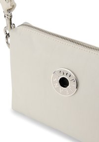 Borsa a mano in nylon beige con un logo circolare argento e cerniera in metallo. Presenta una superficie testurizzata e una tracolla rimovibile.