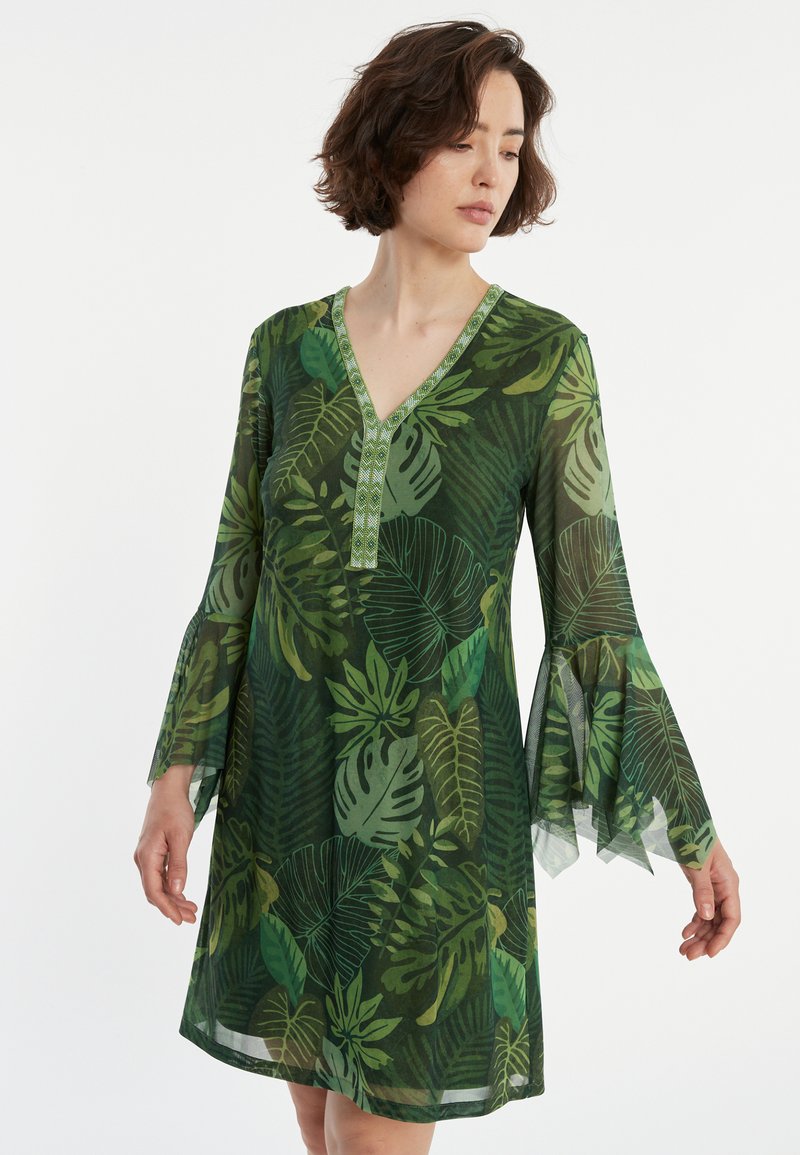 Grün gemustertes Kleid mit Blattdesign, V-Ausschnitt, langen ausgestellt Ärmeln und einer strukturierten Borte entlang des Ausschnitts. Hergestellt aus einem leichten, durchsichtigen Material.