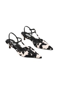 Scarpe slingback a punta affusolata realizzate in pelle bovina bianca e nera, con sottili cinturini neri e un tacco piccolo. Texture piatta con un interno liscio.