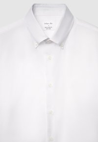 Chemise blanche à boutons avec une coupe régulière. Elle présente un col classique, cinq boutons, et une texture lisse, résistante aux plis.