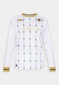 Pitkähihaista valkoista paitaa, jossa on tummansiniset timanttikuviot ja kultaisia yksityiskohtia. Sisältää pyöreän kauluksen ja tekstin "Football Club de Versailles".