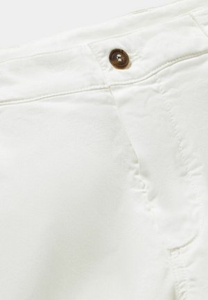 Weiße Stoffshorts mit einem braunen Knopfverschluss, glatter Textur und Nähten an den Seiten, die ein schlichtes und funktionales Design betonen.