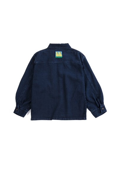 Veste en jean bleu foncé vue de dos avec des manches longues et un petit écusson carré jaune et vert près du col.