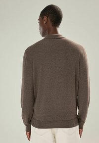 Brauner Strickpullover mit hohem Kragen, gerippten Bündchen und Saum. Der Stoff hat eine weiche Textur und eine gleichmäßige, einheitliche Webart.