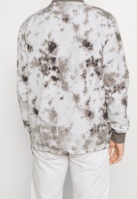 Sudadera en un patrón de tie-dye en blanco y gris. Presenta un corte relajado, cuello redondo y puños de canalé. Fabricada en un tejido suave y ligero.