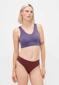 Lilla trådløs bh med teksturerede stropper, parret med maroon højtaljede trusser. Glat stof, minimale sømme og enkelt design.
