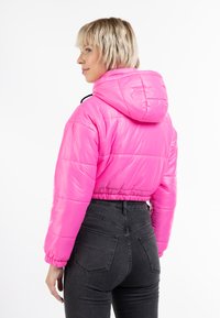 Zkrátená bunda s perím v lesklej horúco ružovej farbe, s kapucňou a elastickými manžetami. Nosené s čiernymi džínsami s vysokým pásom.