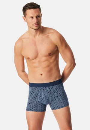 Boxershorts gemaakt van blauw stof met een geometrisch patroon in lichtblauw en koraal, met een effen donkerblauwe elastische tailleband.