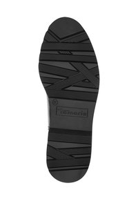 Semelle d'une chaussure Tamaris noire avec un motif de bande de roulement texturé et la taille 37 marquée près du nom de la marque.