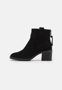 Svart mocka ankelsko med rund tå, sidodragkedja och klack i blockstil. Har en dragflik bak för enkel påtagning.