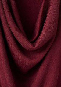 Burgundy fabric draped in soft folds, featuring a lightweight, textured knit with smooth edges. Suitable for garments or accessories.