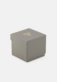 Boîte texturée grise avec un logo triangulaire doré sur le dessus et un design minimaliste. Forme carrée avec fermeture sans couture.