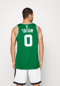 Zelena košarkaška dres s bijelim detaljima, s natpisom "TATUM" i brojem "0" na leđima. Izrađen od prozračnog mrežastog materijala.