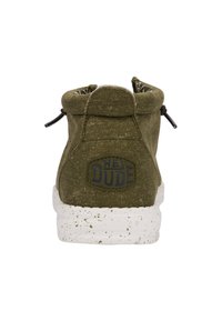 Botín de lona verde oliva con suela moteada blanca, cordones elásticos y un logo azul "HEY DUDE" en la parte de atrás.