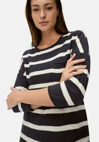 Navy- und weiß gestreiftes Langarmshirt mit rundem Halsausschnitt und Brusttasche. Weicher Stoff; Ärmel in Dreiviertellänge.