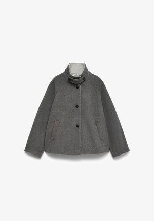 Szürke gyapjúdzseki magasra gombolt gallérral, elöl gombokkal és két oldalsó sliccelt zsebbel, fehér háttéren kifektetve.