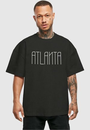Black oversized t-shirt featuring "ATLANTA" in bold white letters. Cotton material with short sleeves and a relaxed fit.