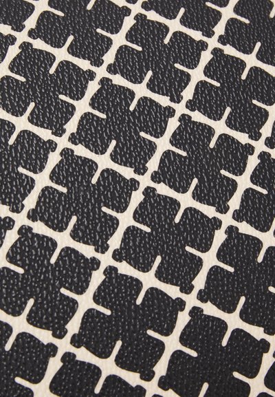 Textured black pattern featuring interlocking shapes on a cream background, showcasing a geometric design and contrasting colors.