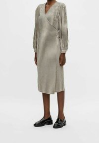 Ruutupintainen ruskea ja kerma midi-mekko, jossa on pitkät puffi-hihat, kietaisu-muotoilu ja sivuhalkio, yhdistettynä mustiin loafer-kenkiin.