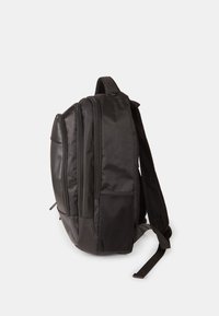 Mochila negra con múltiples compartimentos con cremallera, correas acolchadas negras, bolsillo lateral de malla y un acabado de material suave.