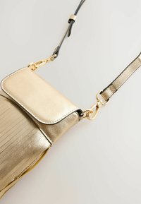 Goldfarbene Leder-Umhängetasche mit strukturiertem Finish, Klappenverschluss und schwarzen Lederelementen. Verfügt über einen Verschluss aus goldfarbenem Metall.