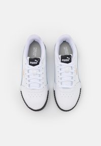 Bílé tenisky s hladkým koženým povrchem, plochými tkaničkami, polstrovaným jazykem a texturovanou černou gumovou podrážkou; mají stříbrný akcentový proužek.