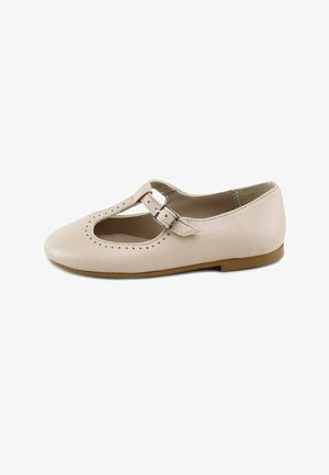 Zapato plano Mary Jane de cuero beige con tira en T, cierre de hebilla, pequeños orificios decorativos perforados y suela de color marrón claro.