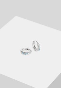 Sølvøreringe med blå ædelstene langs den ene side; glat tekstur med en poleret finish. Kompakt, cirkulær form.