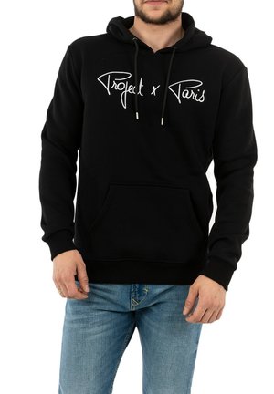 Zwarte katoenen hoodie met een voorzak, verstelbare trekkoorden en witte tekst "Project x Paris" over de borst. Casual fit en ribbelmanchetten.