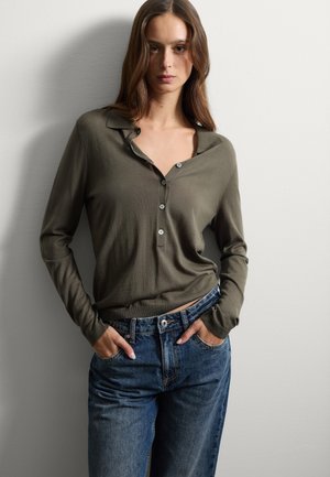Olijfgroene langesleeve shirt met een kraag en knoopdetails, gecombineerd met hoge taille, relaxte blauwe jeans.