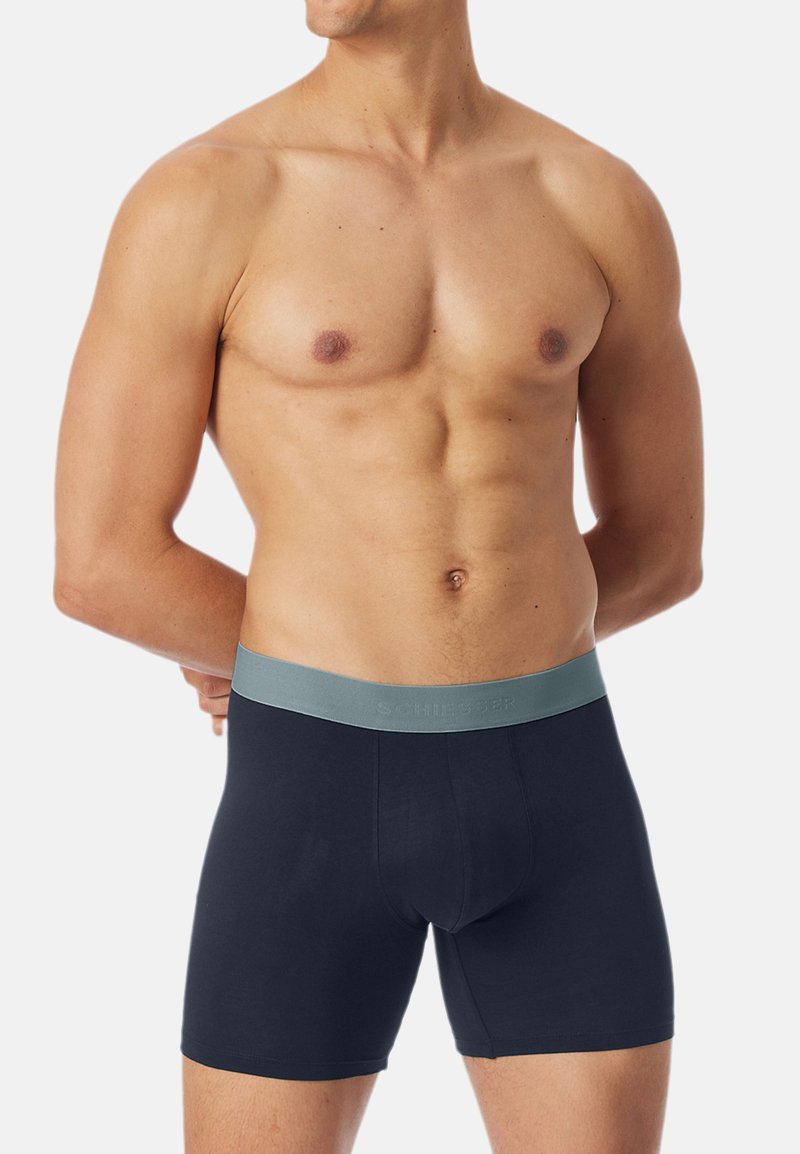 Zwarte boxershorts gemaakt van een soepel stof met een lichtgrijze tailleband met reliëflogo; aansluitende pasvorm en lengte tot halverwege de dij.