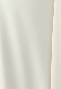 Tissu lisse de couleur blanc cassé avec une texture diagonale subtile et de doux plis naturels.