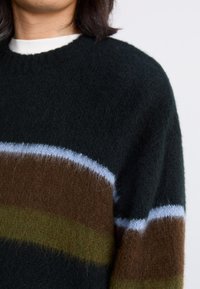 Strik jumper med mørkegrønne, brune og lyseblå striber. Blød tekstur med klassisk rund halsdesign.