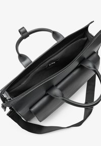 Bolso de cuero negro con asas superiores, cierre de cremallera y correa de hombro desmontable. Presenta un interior espacioso con un forro de tela oscura.