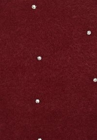 Bordó kötött anyag, puha tapintással, változó méretű, szétszórt rhinestone díszítéssel, ami finom csillogást kölcsönöz.