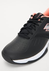 Black athletic shoe with textured upper, pink accents, and perforations. Features a lace-up design and a white midsole.