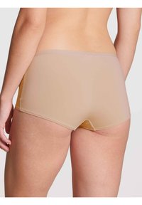 Beige boyshorts gemaakt van zacht materiaal, met een naadloos ontwerp, een lage taille snit en een subtiele elastische tailleband.