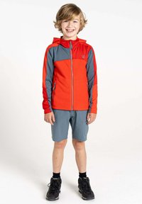 Jungenjacke in Rot und Grau, mit Reißverschluss und Kapuze, kombiniert mit grauen Shorts und schwarzen Wanderschuhen. Der Stoff scheint leicht und strukturiert zu sein.