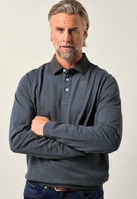 Tmavě modrá polokošile s dlouhým rukávem a kontrastním černým límečkem, s klopou na tři knoflíky a nenápadným logem na hrudi. Standardní střih.